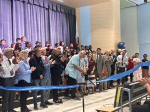 Group of people in auditorium cutting ribbon for ceremony